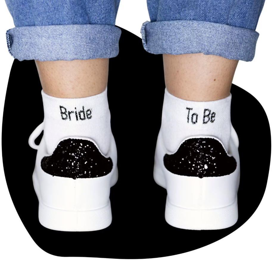 (Chaussettes Bride to be )Chaussettes blanches avec une écriture noir . Sur la chaussette gauche est écrit "Bride" et sur la droite "To be". Donc l'ensemble fait une paires de chaussettes "Bride To be" pour les future mariées