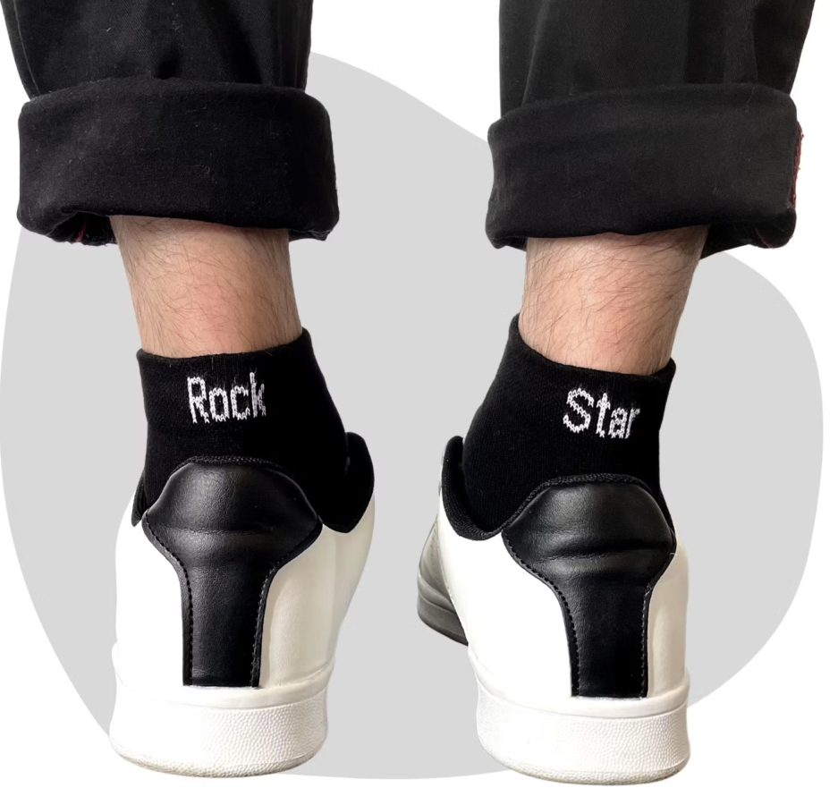 (Chaussettes Rock Star Noir) Chaussettes noirs avec une écriture blanche. Sur la chaussette gauche est écrit "Rock" et sur la droite" Star". Les deux ensemble font une paire de Chaussettes Rock Star