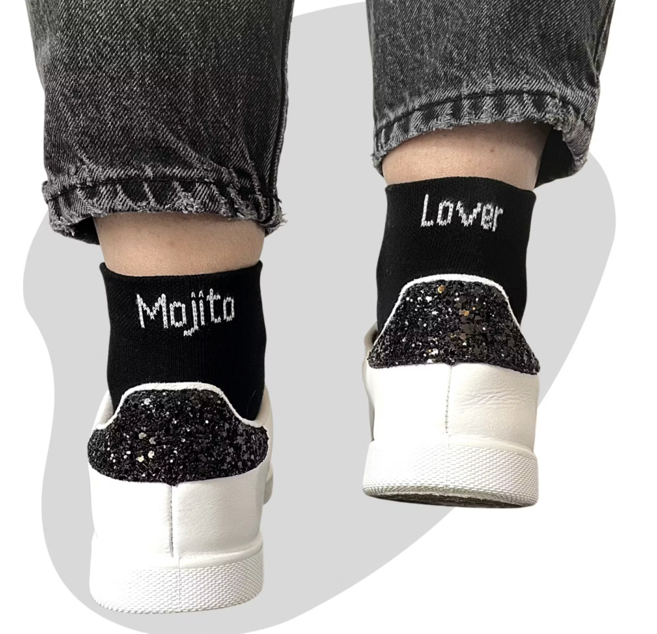 (Chaussettes Mojito Lover) Chaussettes noir avec une écriture blanche. Sur la chaussette gauche est écrit "Mojito" et sur la droite "Lover". L'ensemble fait une paires de Chaussettes Mojito Lover