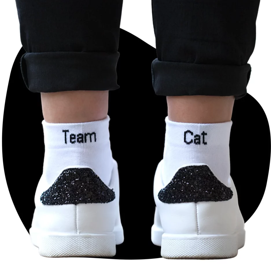 Paire de chaussettes dépareillées blanche Team Cat. On retrouve le mot "Team" à l'arrière de la cheville gauche et "Cat" à l'arrière de la droite.